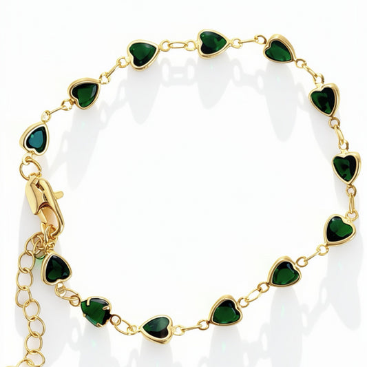 A gold chain bracelet featuring multiple heart-shaped green enamel inlays, displayed on a clean white background with soft reflections.